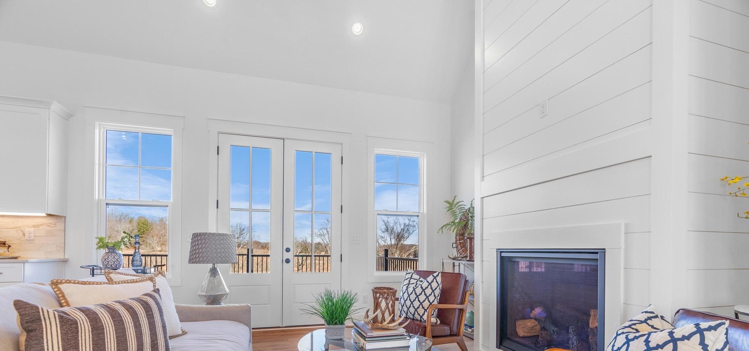 Finished living room with a vaulted ceiling, shiplap fireplace, and French doors