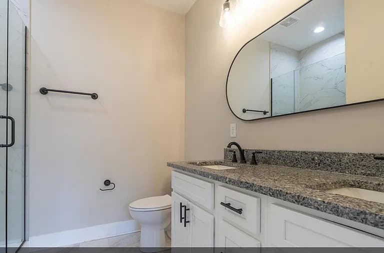 Bathroom with double vanity, granite counters, and glass shower — S&T Construction