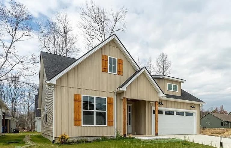 Front elevation with covered entry and two-car garage — The Daly by S&T Construction
