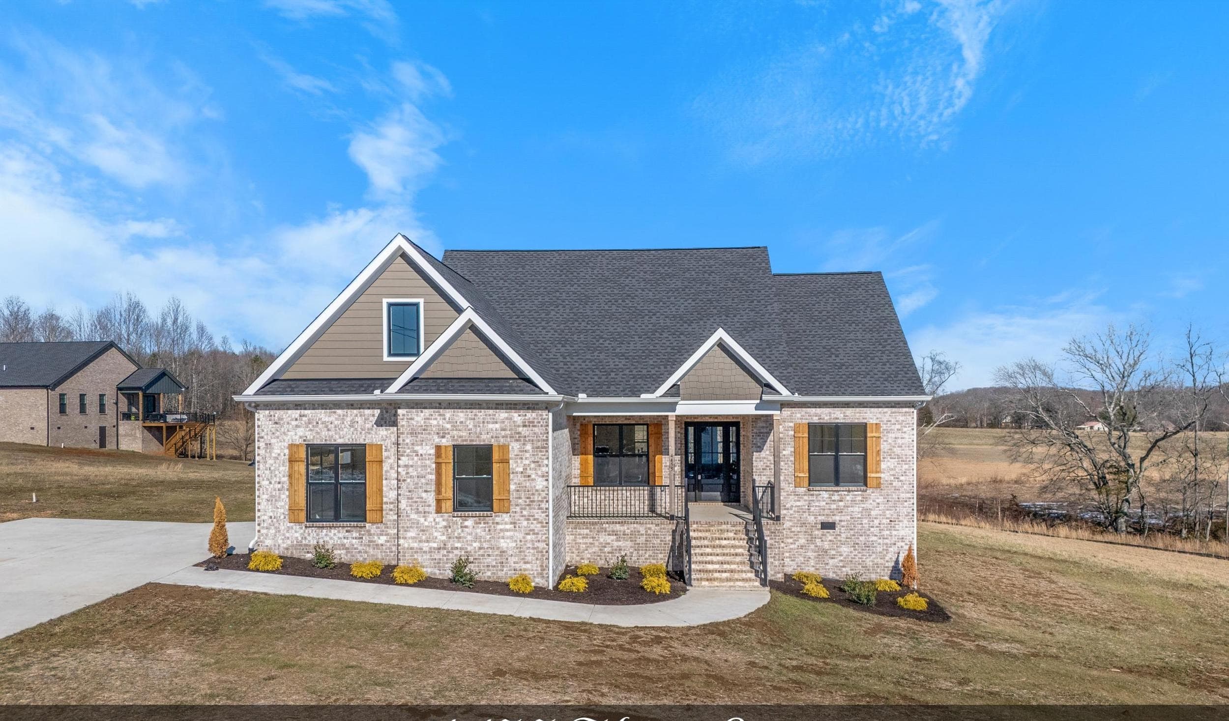 Brick custom home with wood shutters, a covered entry, and a landscaped walkway