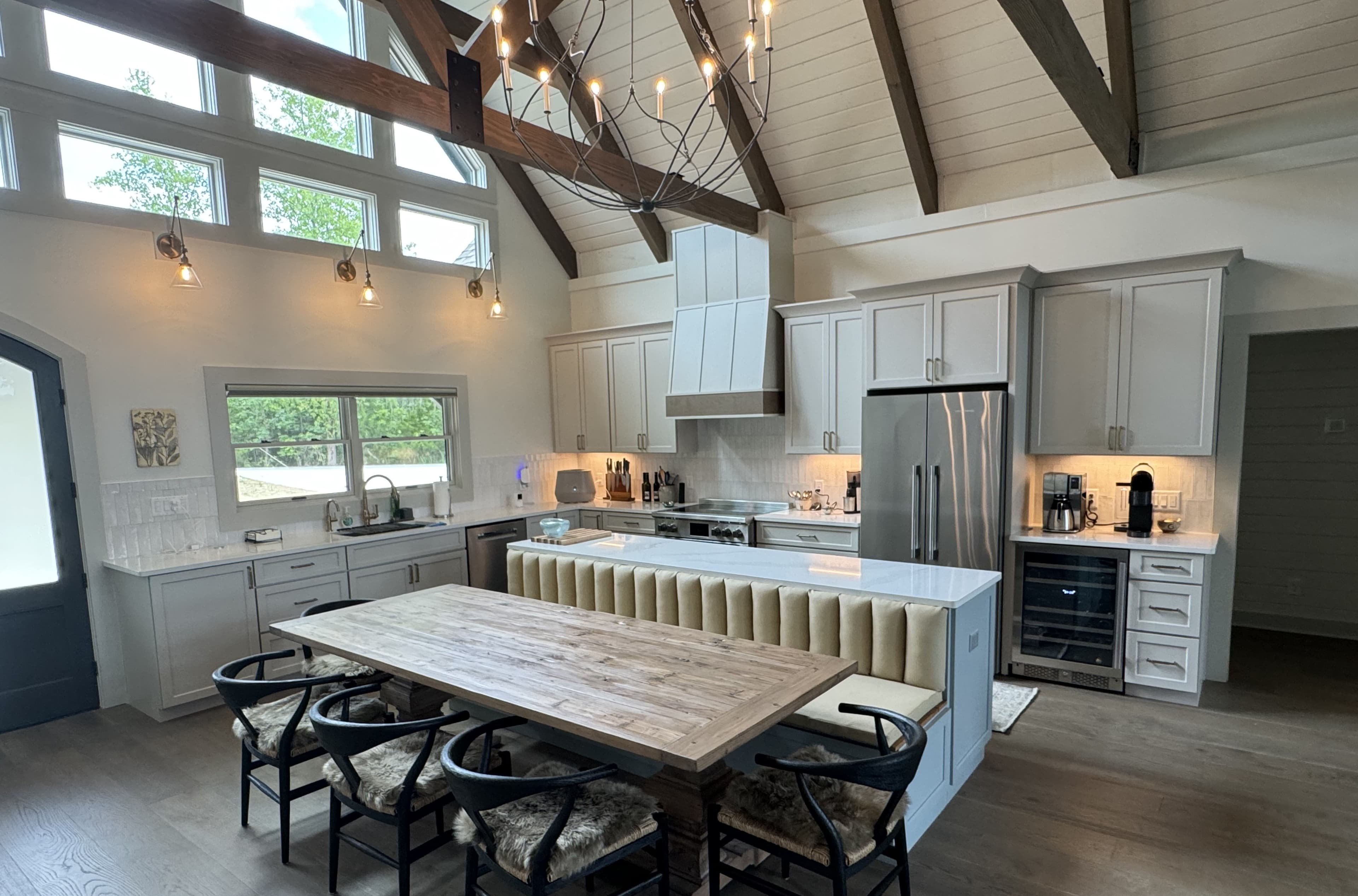 Custom home kitchen with vaulted shiplap ceiling, exposed beams, and chandelier — built by S&T Construction