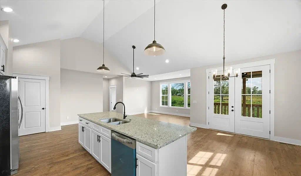 Open-concept living area with vaulted ceiling and French doors — The Kaley by S&T Construction