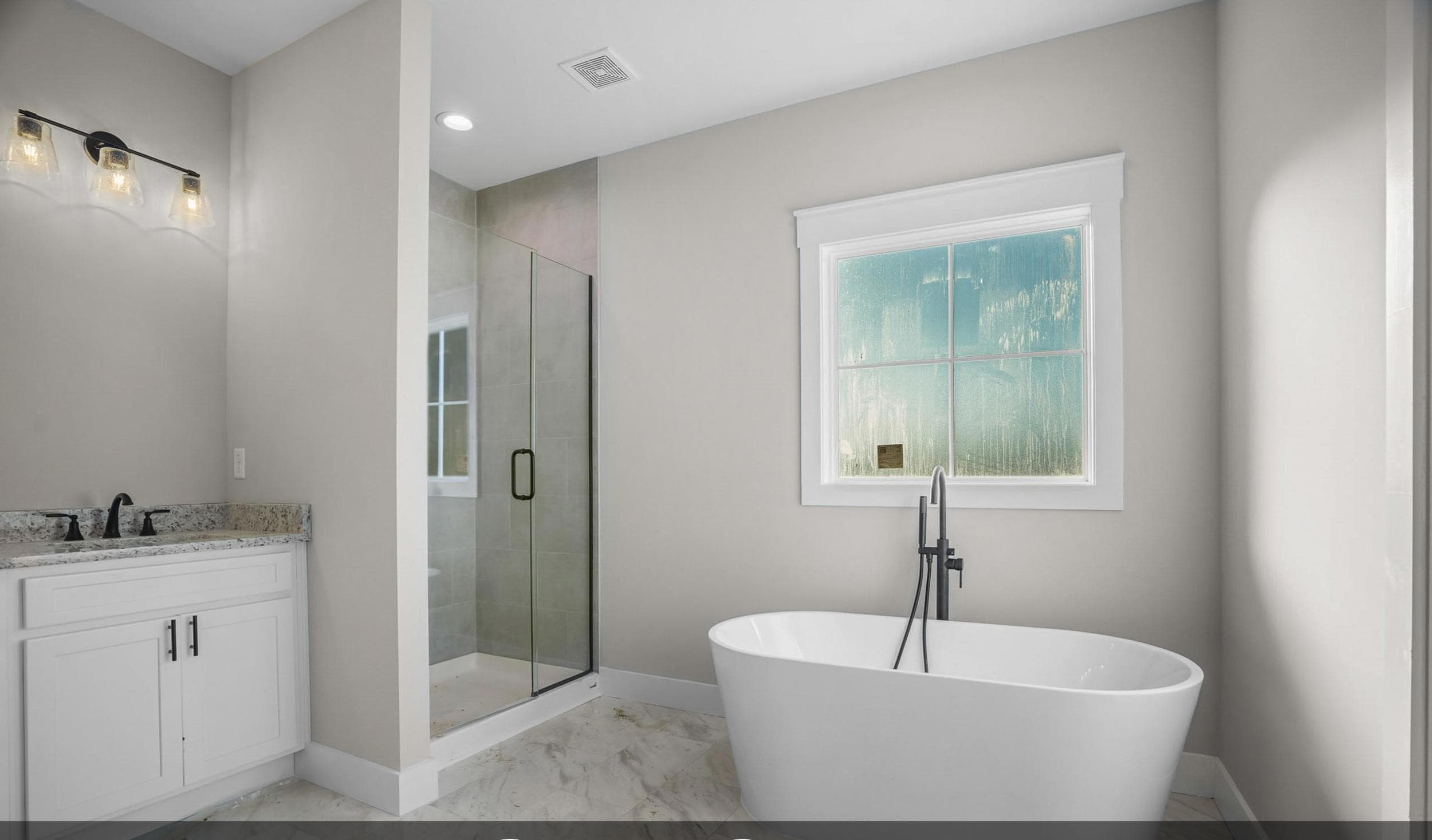 Finished primary bathroom with a freestanding tub and glass-enclosed tile shower